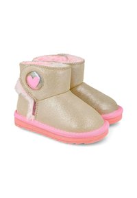 Botas de tobillo doradas brillantes con suela rosa, forro de piel de piel de cordero suave en rosa y un acento de corazón circular en el lado exterior. Exterior texturizado.