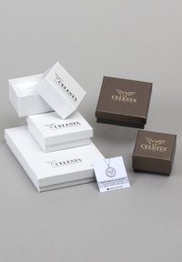 Tre scatole regalo bianche e una marrone, con il marchio "CELESTA" in oro. Sono inclusi una collana d'argento e un biglietto di ringraziamento.