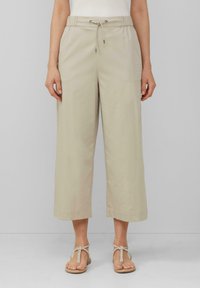 Pantalons beige, légers, coupés avec une taille élastique, un cordon de serrage et deux poches latérales. Texture lisse avec une coupe décontractée.