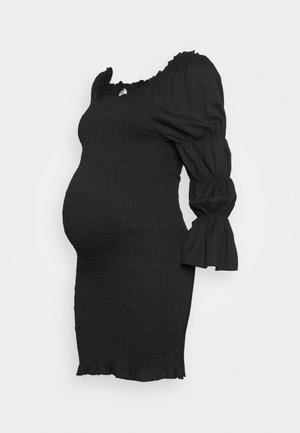 Veste de maternidade preta com textura franzida, decote à off-the-shoulder, mangas bufantes e barra com babados, projetada para um silhueta ajustada.