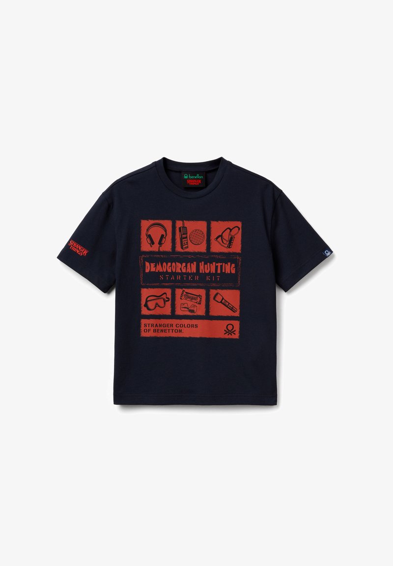 Námořnicky modré tričko Stranger Things s červenými grafikami zobrazujícími sluchátka, baterku, brýle, vysílačku a text "Sada pro začátečníky lovu Demogorgona."