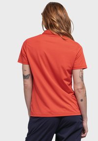 Kurzarm-Poloshirt in leuchtendem Orange, aus strukturiertem Stoff. Mit klassischem Kragen und gerader Saum.