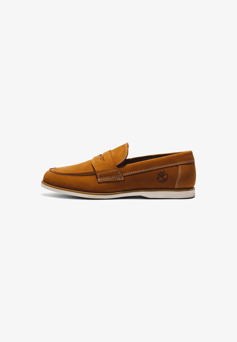 Mocassin marron en cuir à enfiler avec semelle blanche et détails cousus, montrant un profil latéral et un logo d’arbre de la marque près du talon.