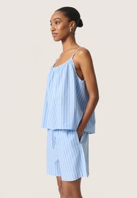 Haut sans manches rayé bleu clair avec un col froncé et un short assorti, doté de poches latérales et d'une coupe décontractée. Tissu en coton.