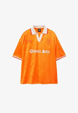 Leuchtend orangefarbenes Sport-T-Shirt mit kurzen Ärmeln, weiß-rotem Kragen, "ORANGE SOUL" Schriftzug und einem Löwenwappen auf der Brust.