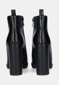 Botines de cuero negro hasta el tobillo con un alto tacón cuadrado, que cuentan con una cremallera en la parte trasera y una textura suave y elegante.