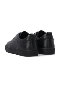 Czarne skórzane sneakersy z plecionym wzorem po bokach, okrągłym noskiem, sznurowanym zapięciem i płaską gumową podeszwą o teksturowanym wykończeniu.