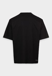 Černé tričko s krátkým rukávem vyrobené z bavlněné tkaniny. Má kulatý výstřih se svým stylem a rovný lem, s malou značkovou etiketou vlevo dole.
