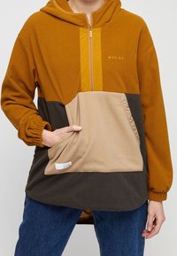 Hooded fleece pullover in oranje, beige en donkergrijs. Kenmerkt een halve ritssluiting aan de voorkant, grote voorkant zak, elastische manchetten en zijopeningen.