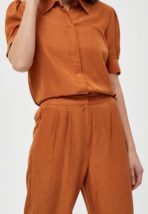 Rood-oranje shirt met een klassieke kraag en korte opgerolde mouwen, gecombineerd met bijpassende broek met een subtiel textuurpatroon.