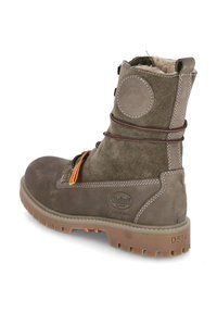 Bottines en cuir suédé marron à lacets, avec un col rembourré, une semelle en caoutchouc et un patch logo sur le côté.