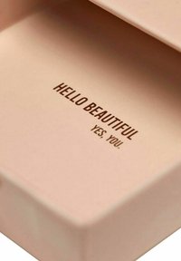 Rektangulär rosa ask med slät matt yta; insidan har upphöjd brun text: "HEJ VACKRA JA. DU."