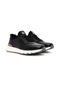 Zwarte sportieve schoenen met een slanke, gladde leren bovenkant, witte tussenzool en rubberen buitenzool; met contrasterende bruine accenten en vetersluiting.