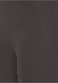 Zwarte legging gemaakt van rekbare, gladde stof met een matte afwerking. Voorzien van een hoge tailleband en geen zichtbare naden voor een gestroomlijnd uiterlijk.