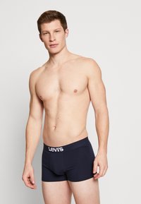 Marineblaue Boxershorts mit einem weißen "Levi's"-Logo am Bund, aus weichem, dehnbarem Material. Enganliegendes Design.
