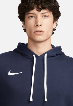 Marineblaues Hoodie aus weichem Stoff, mit einem weißen Nike-Logo auf der linken Brust und weißen Kordeln für die Kapuze.