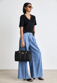 Sort V-hals T-shirt, lyseblå vidde denim bukser, sort quiltet håndtaske med gulddetaljer og sorte slide-sandaler.