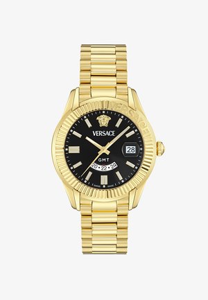 Gold-tone metal watch with a black dial, featuring a GMT display, date window, and luminous hour markers. Decorative bezel and linked bracelet.