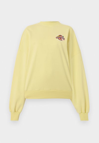 Sweat-shirt jaune clair à col rond avec manches longues bouffantes et petit logo coloré "Stieglitz" sur la poitrine gauche.