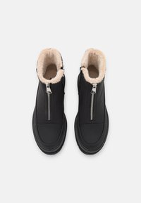 Sorte skinn ankelstøvler med myk kremfarget faux fur-fôr, sideskuffer og rund tå-design. Solid gummisåle.
