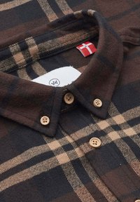 Bruin en zwart geruit flanellen shirt met een button-down kraag. Voorzien van beige knopen en een Deense vlaglabel. Zachte textuur met een warme uitstraling.