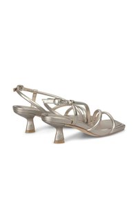 Metallic zilveren sandalen met hak, voorzien van meerdere dunne bandjes, een vierkante neus en een kenmerkende schuine hak. Glad textuur zonder zichtbare patronen.