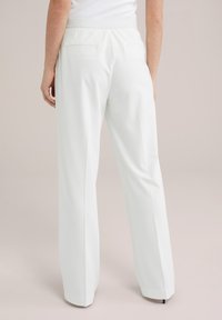 Pantaloni bianchi su misura con un design a gamba dritta. Presentano un tessuto liscio, una vita elastica e due tasche posteriori.