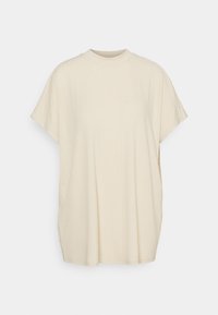 Ljusbeige kortärmad t-shirt med rund halsringning, tillverkad av mjukt tyg med en subtil ribbad struktur. Lös passform med sidsömmar.