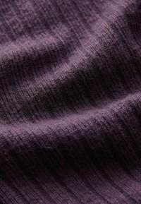 Purple textured fabric with a ribbed pattern, showing varying shades and a soft, woven appearance.