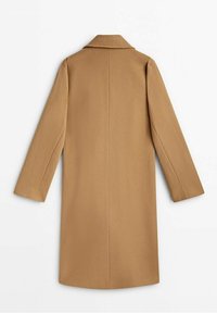 Long manteau camel avec col cranté, coupe droite et manches longues. Confectionné dans un tissu lisse, il présente des lignes épurées et aucun système de fermeture visible.