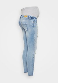 Light blue maternity skinny jeans with distressed accents, featuring a stretchy gray waistband for comfort and a fitted design.