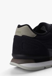 Tenis negri cu textură din suede, având un accent gri și panouri din plasă. Talpă albă și gri, cu un design rotunjit. Numele brandului pe toc.