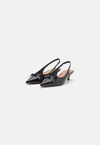 Sorte lakkert skinn slingback hæler med spiss tå, liten hæl og dekorativ sløyfe foran. Jevn tekstur.