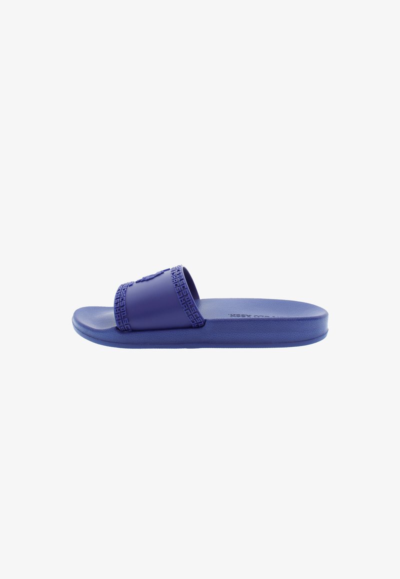 Purple slide sandal made of rubber with a textured strap, flat sole, and logo detail on the strap. Smooth, durable surface throughout.