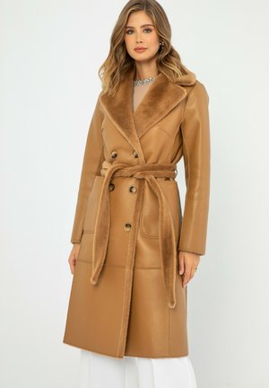 Bruine neplederen jas met een brede faux-bont kraag, dubbele knopen, een ceintuur om de taille en voorzakken. Gladde textuur, middenlengte ontwerp.