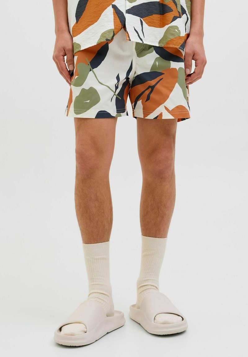 Heren shorts met een witte basis en groene, oranje en zwarte bladranden. Voorzien van een lichtgewicht stof met een relaxte snit.