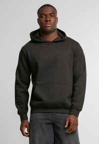 Felpa con cappuccio grigia scura, realizzata in tessuto morbido. Presenta una tasca frontale a marsupio e polsini a costine, con un design semplice e pulito.