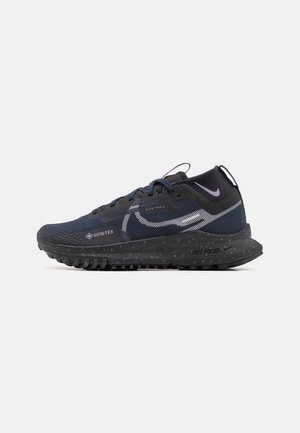Navy trail running shoes featuring a mesh upper, reflective accents, Gore-Tex branding, and a textured rubber outsole for traction.