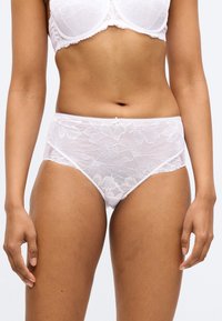 Białe figi typu hipster z koronkowymi kwiatowymi wzorami, ozdobione koronką z falbanką i małą kokardką z przodu. Miękka tekstura i elastyczne dopasowanie.