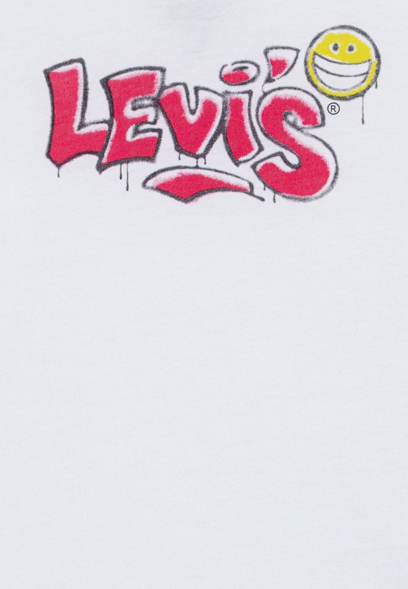 Camiseta de algodón blanca con un logo de "Levi's" en estilo graffiti rojo y una cara sonriente amarilla con contornos negros encima del texto.