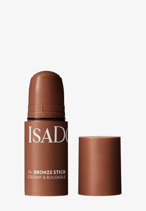 Brauner zylindrischer Stift IsaDora Bronze Stick cremiges und aufbaubares Make-up mit abgenommenem Deckel, der daneben liegt.