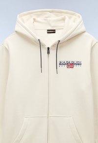 Felpa color crema con chiusura a zip, due tasche frontali, cappuccio con cordino regolabile e logo grafico NAPAPURI sul petto.