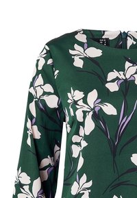 Grön blommig blus med långa ärmar. Har mönster av vita och lila irisar, något slätt tyg och dragkedja i ryggen. Stl EUR 36.