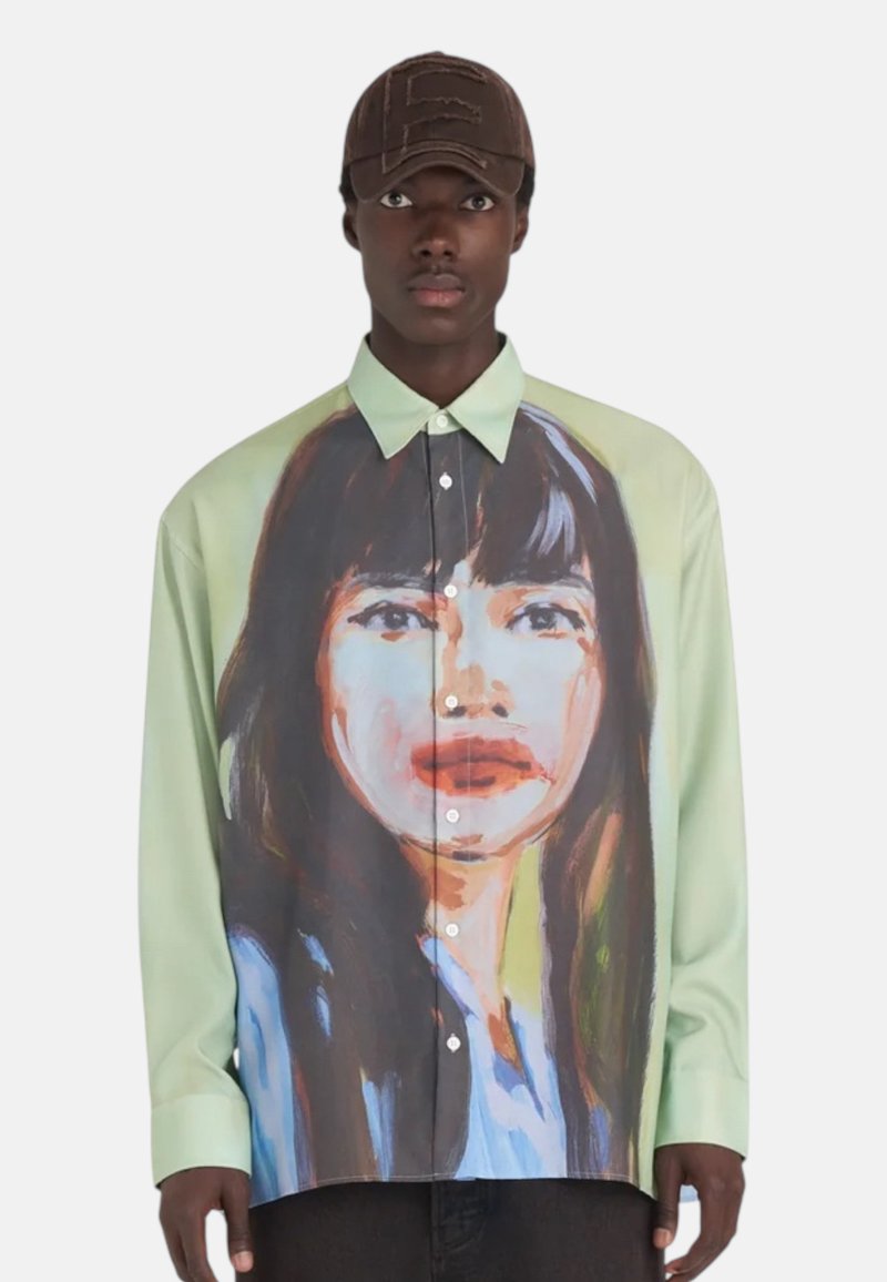 Chemise verte à boutons avec une grande impression de portrait abstrait à l'avant. Tissu lisse avec un col classique et une coupe structurée.