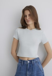 Light blue cropped t-shirt with a ribbed texture and short sleeves, paired with high-waisted denim shorts featuring a button closure.