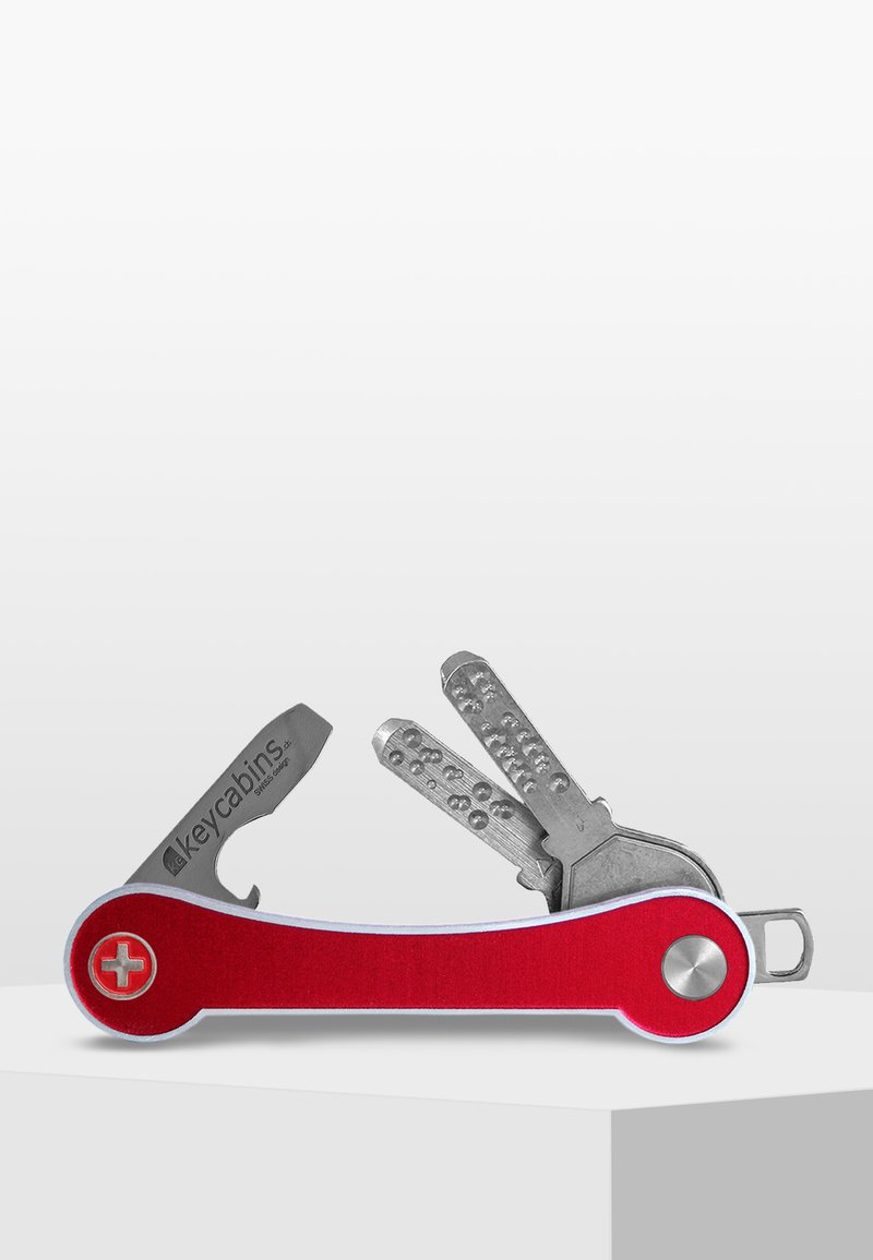  porte-clés rouge avec un couteau métallique et plusieurs formes de clé, arborant une surface texturée et un logo d'un côté. Accent circulaire argenté.