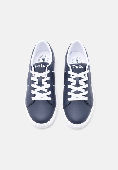 Αθλητικά παπούτσια Polo σε ναυτικό μπλε με λευκά κορδόνια και σόλες, θέα από πάνω που δείχνει το όνομα της μάρκας στη γλώσσα και το λογότυπο μέσα στο παπούτσι.