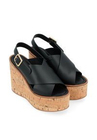 Sandali slingback neri in pelle con design a fascia incrociata, dotati di tacco in sughero e accentuati da una fibbia dorata. Texture liscia.