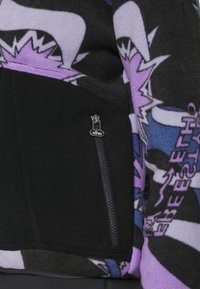Zwarte fleecejack met een kleurrijke grafische print in paars, blauw en zwart. Inclusief een ritszak met een zilveren trekker.