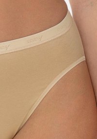 Culotte en mélange de coton beige avec une ceinture douce affichant un logo discret. Texture lisse et coupe classique pour un confort et un ajustement optimal.